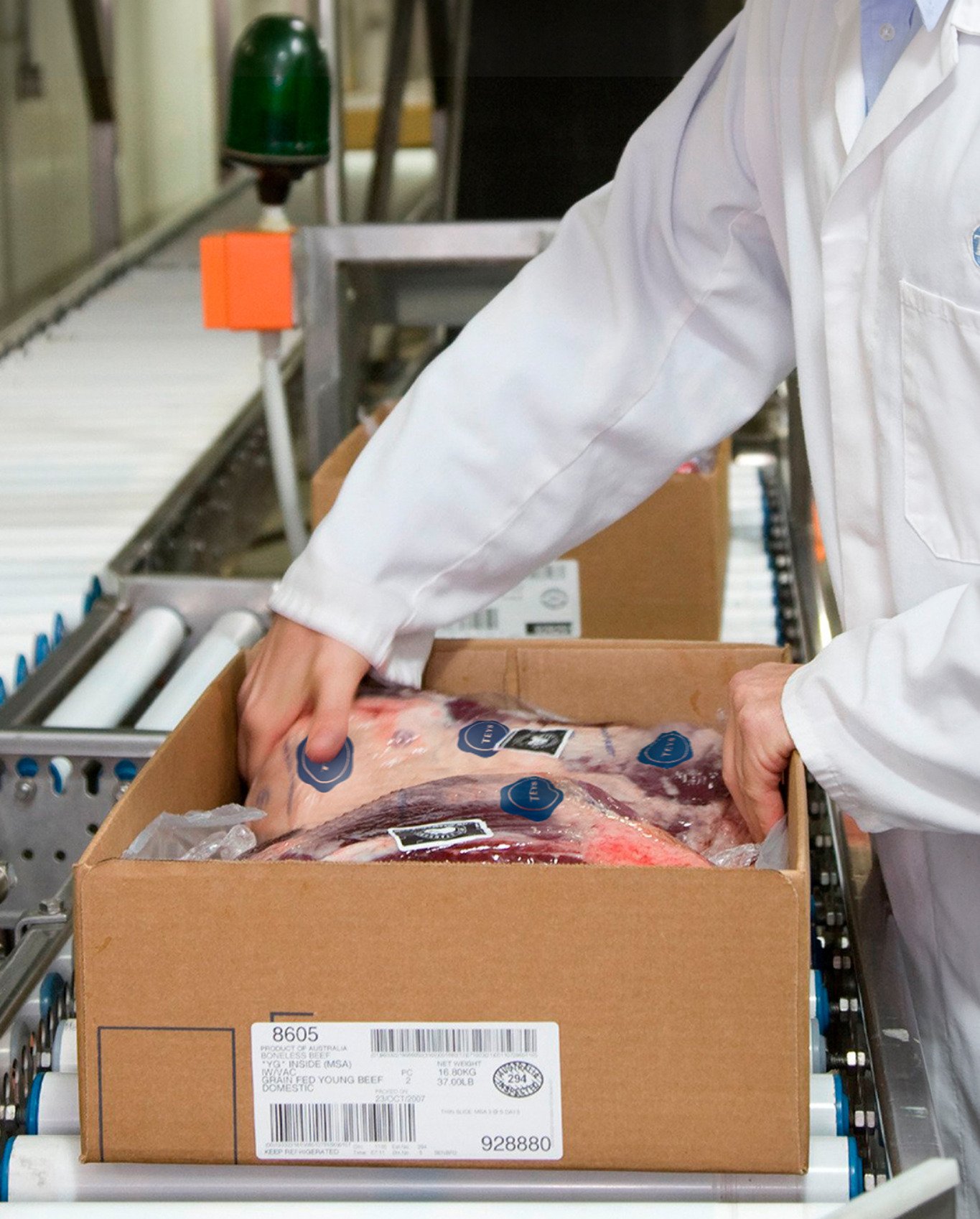 A worker packs meat product into a box