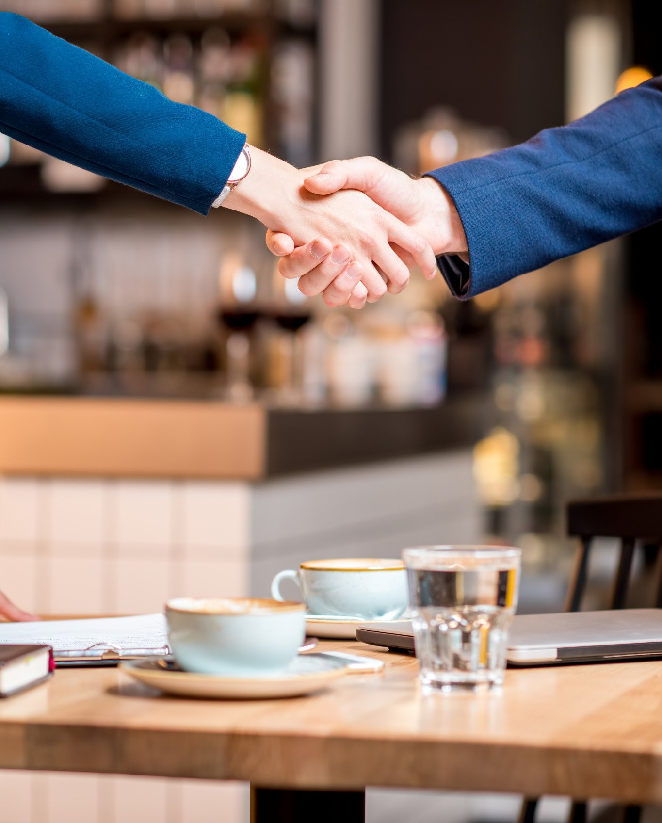 Two people shaking hands over a casual coffee