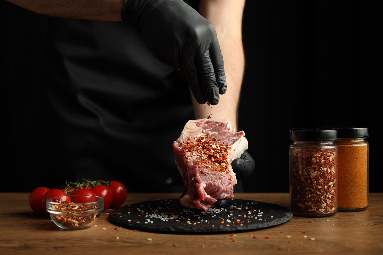 Hand carefully seasoning premium beef with spices.