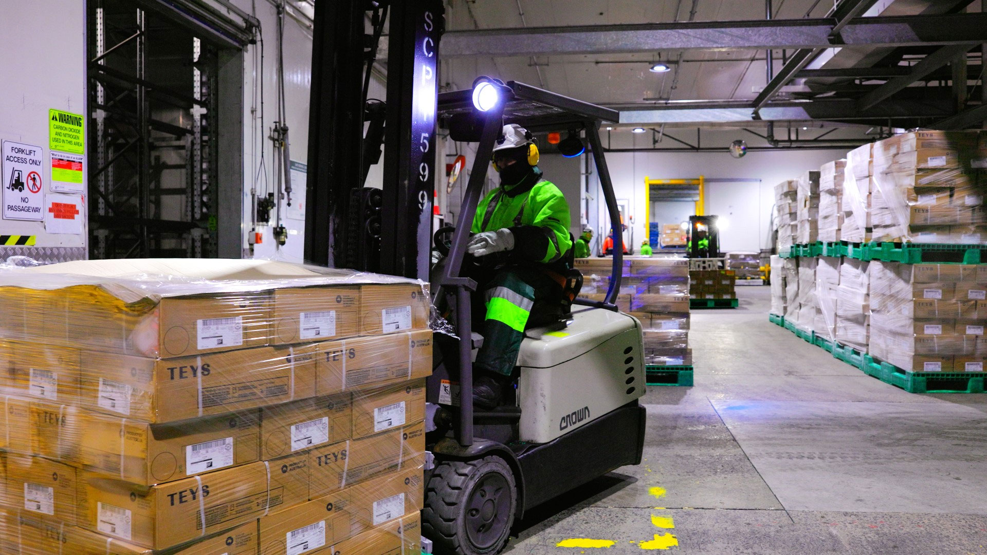 Workers move palettes in a warehouse