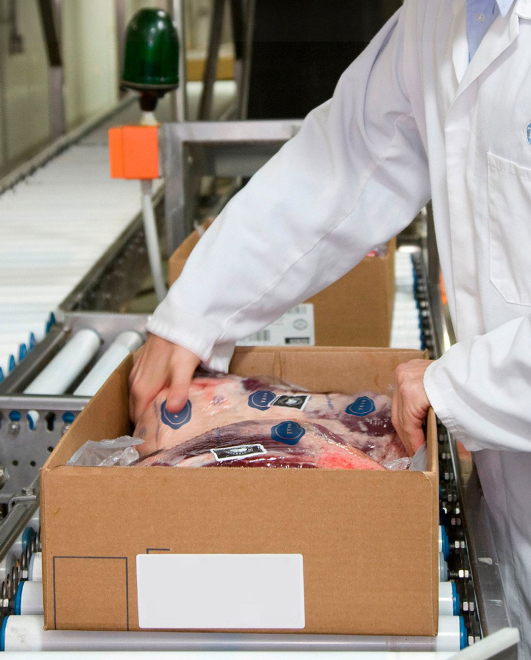 A worker packs meat product into a box