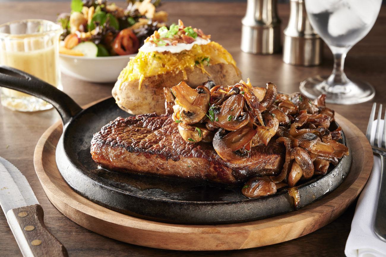 A steak served with mushrooms and a baked potato